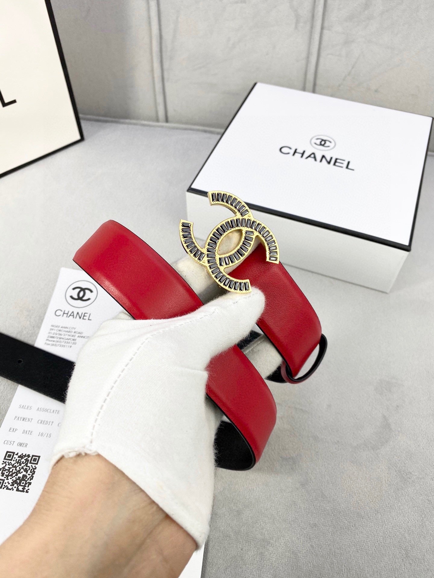 Chanel belt worn by hand, red leather strap with CC logo buckle and black lining