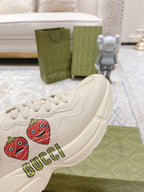 White sneaker close-up with strawberry patch and GUCCI logo on side panel