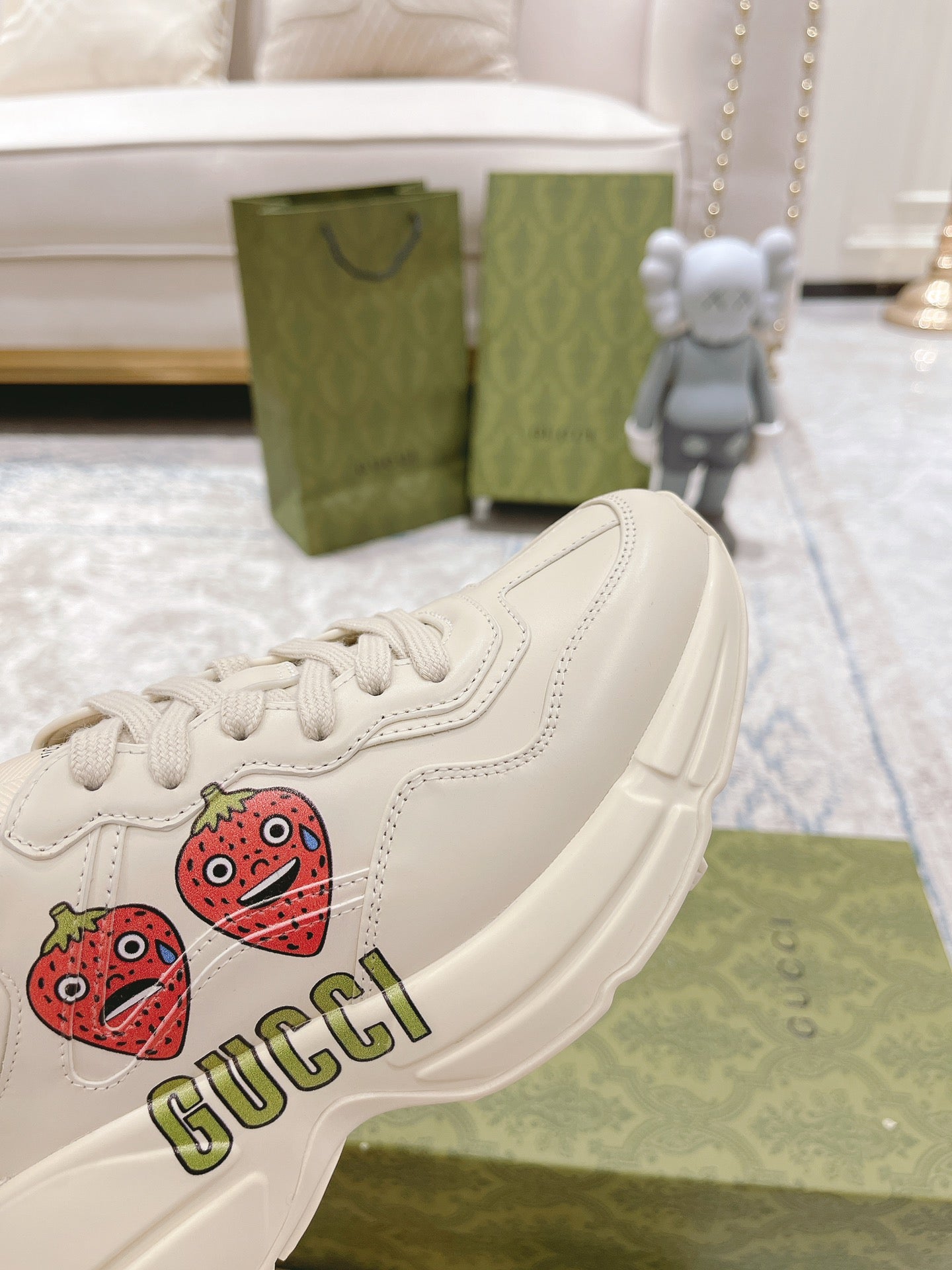 White sneaker close-up with strawberry patch and GUCCI logo on side panel