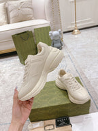White leather sneakers with lace-up front, showing chunky sole and logo