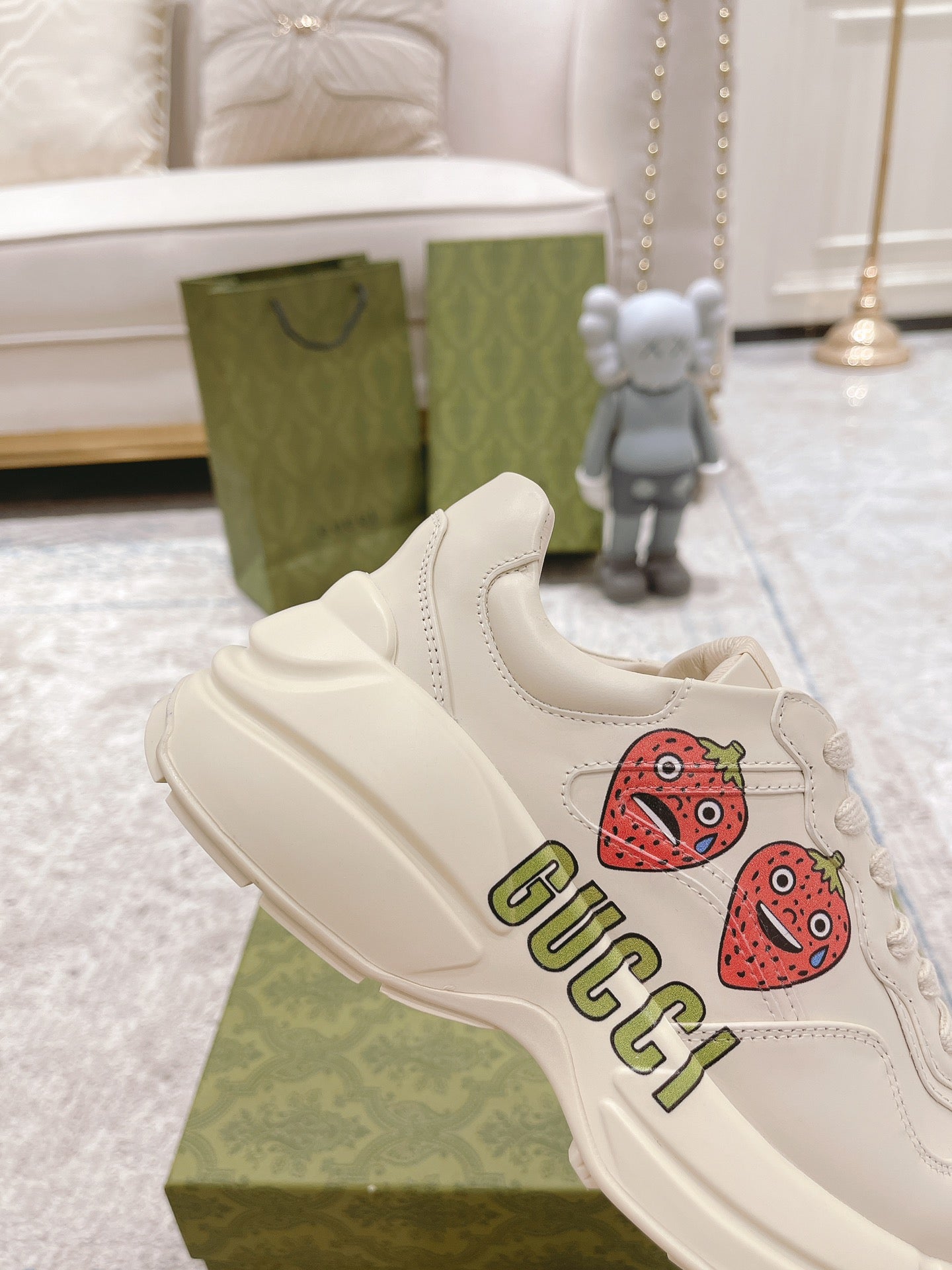 White leather sneakers with strawberry patches and GUCCI logo, side close-up