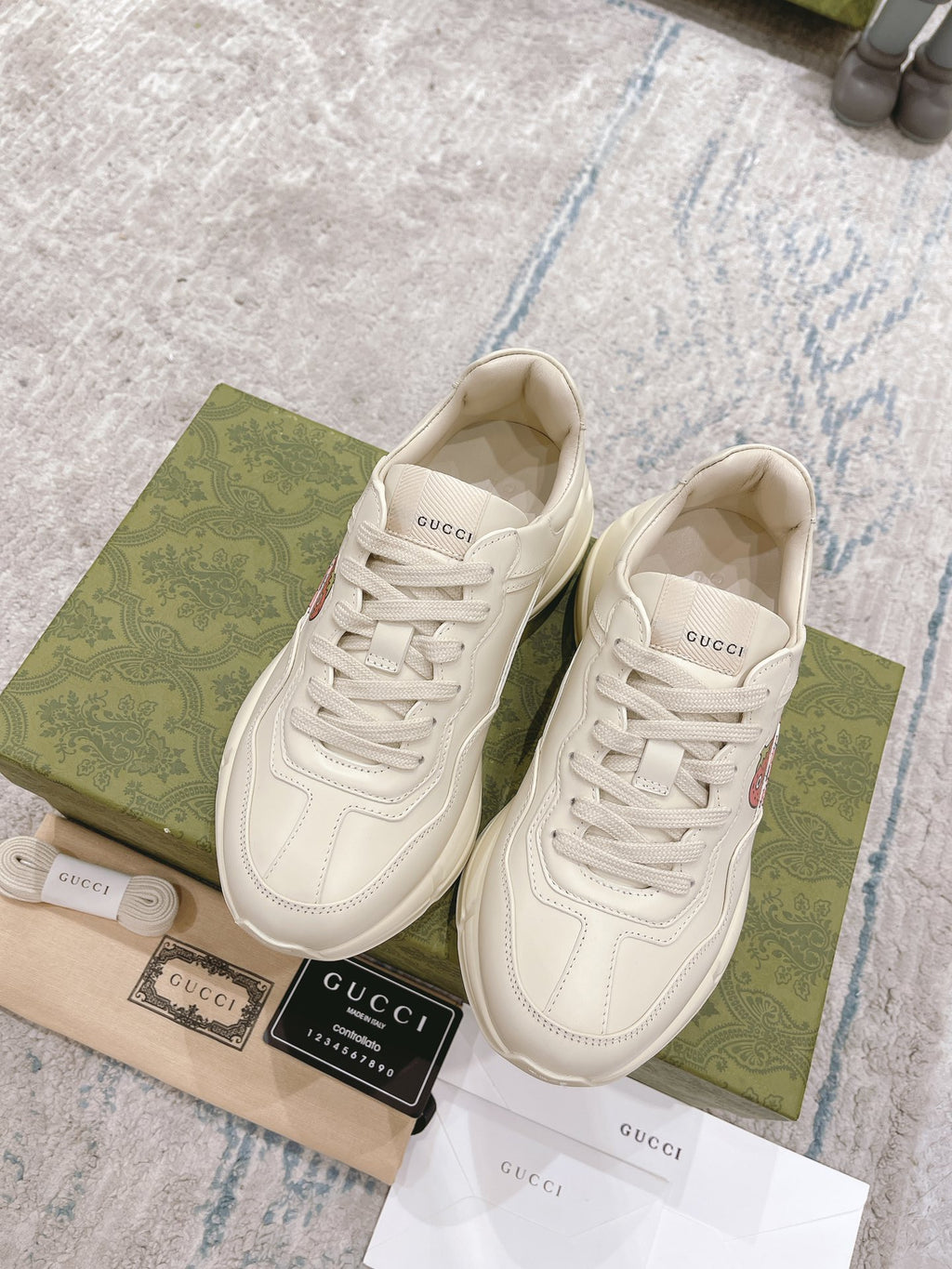White leather lace-up sneakers, front view, GUCCI logo and strawberry appliques