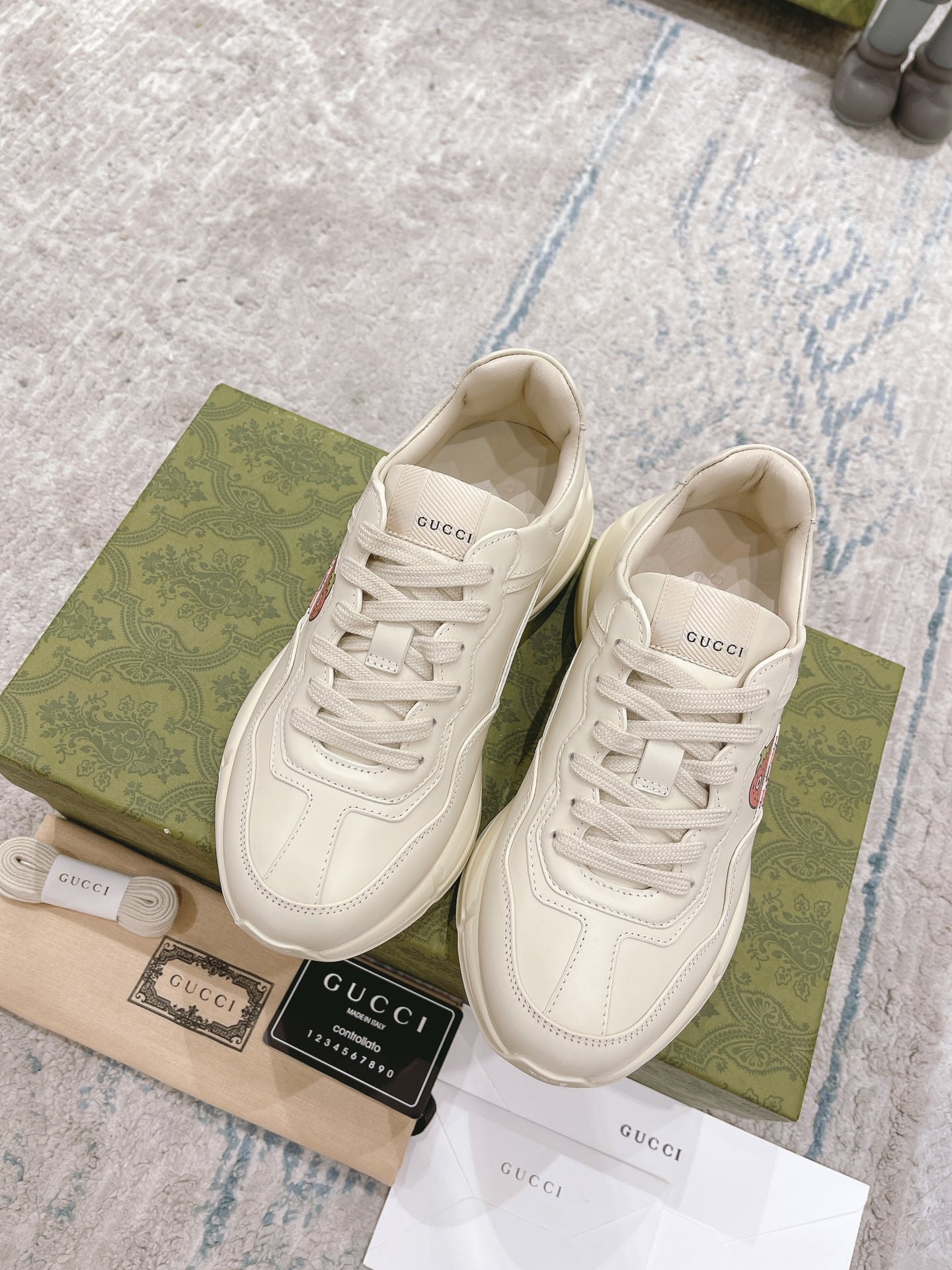 White leather lace-up sneakers, front view, GUCCI logo and strawberry appliques