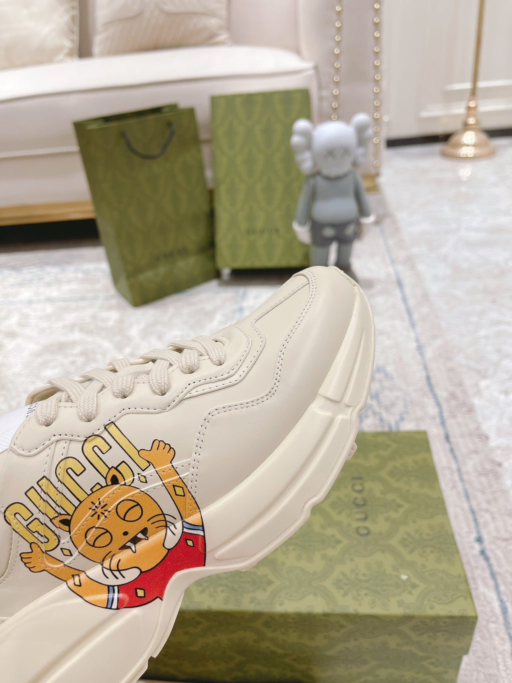 White Gucci sneaker side view with cartoon logo emblem and lace-up eyelets