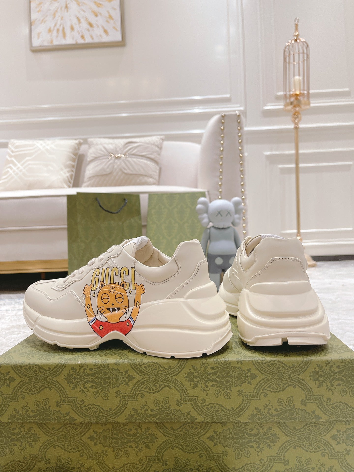 Pair of white Gucci sneakers showing heel, side panel, and cartoon emblem
