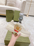 White Gucci sneaker held by hand, showing side stitching and cartoon patch