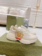 White unisex Gucci sneakers with cartoon logo patch and lace-up front