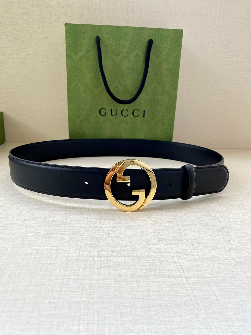 Navy leather belt with gold GG buckle on center, looped strap and perforations
