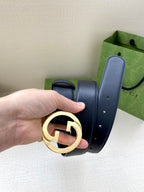 Dark blue leather belt close-up with gold GG buckle and punched adjustment holes