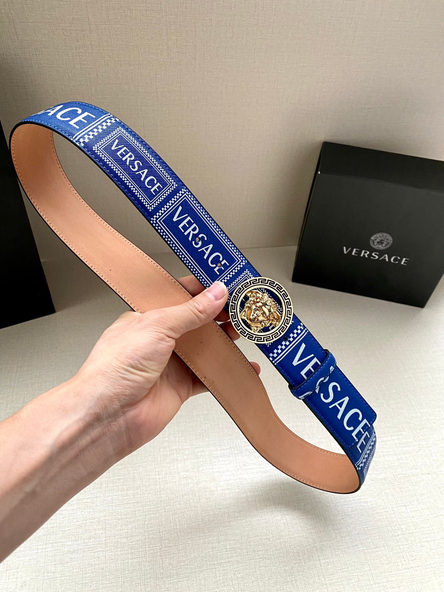 Versace belt held up: blue strap with gold-tone round medallion buckle and tan lining