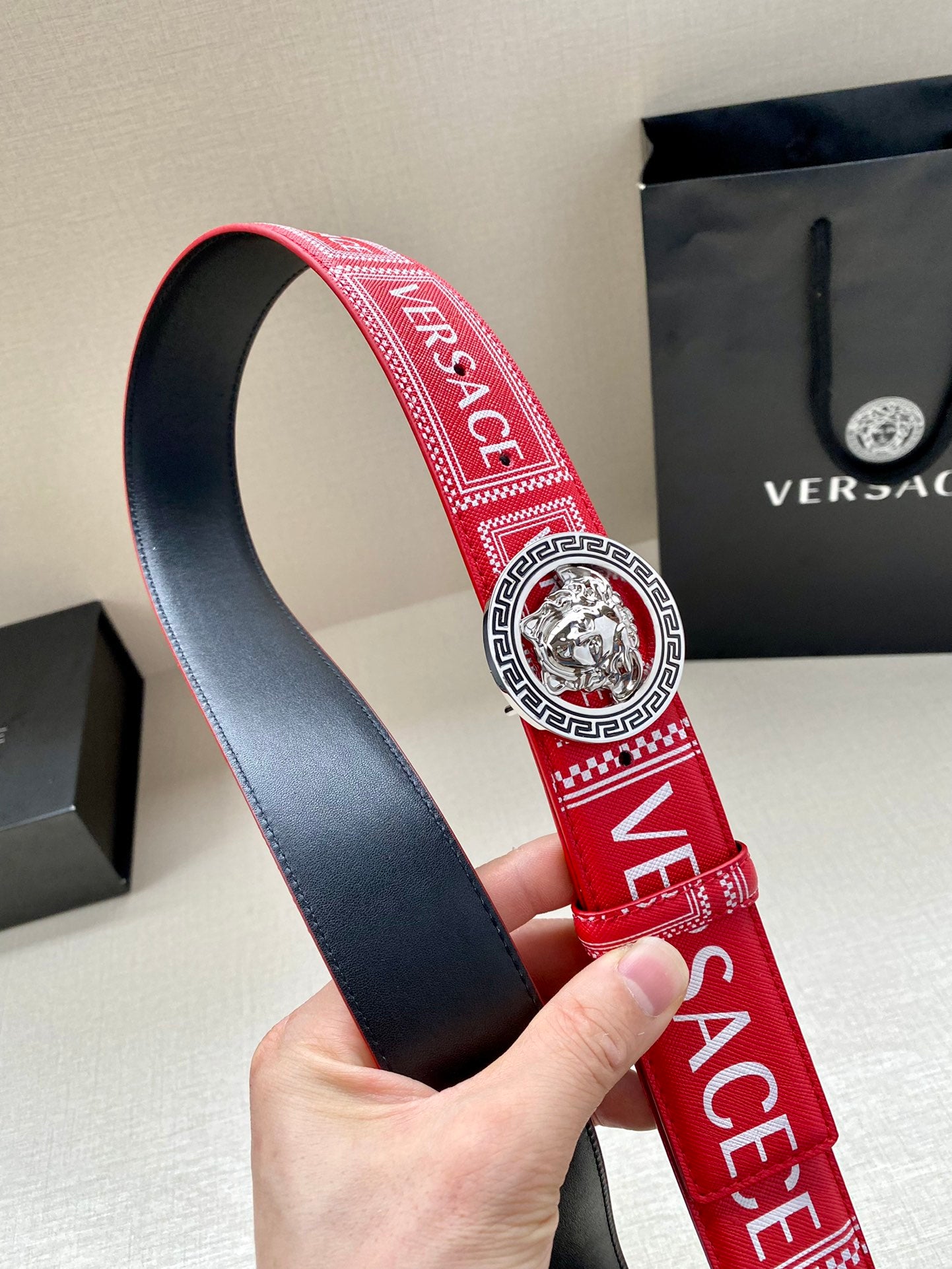 Versace belt showing red strap lining with navy underside and lion buckle