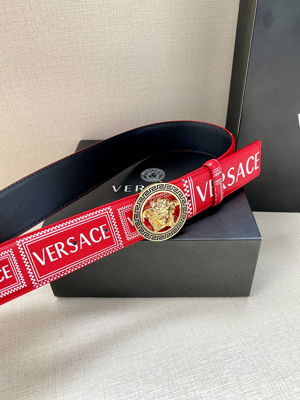 Versace belt with red logo strap, navy edges, and circular lion buckle