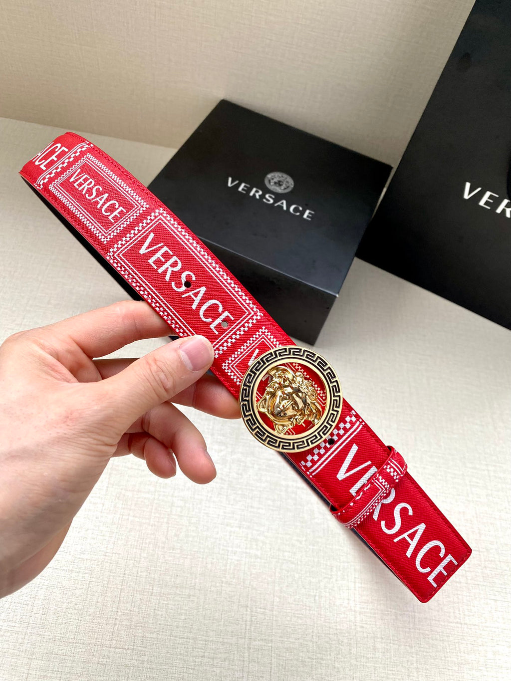 Versace belt with red patterned strap and circular gold lion buckle