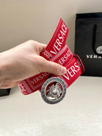 Versace belt held upright, red logo strap with circular lion buckle