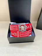 Versace belt in open box on cushion, red logo strap with lion buckle