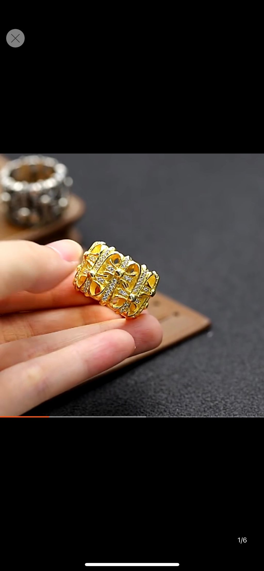 Gold-tone crystal-studded chrome ring held in hand