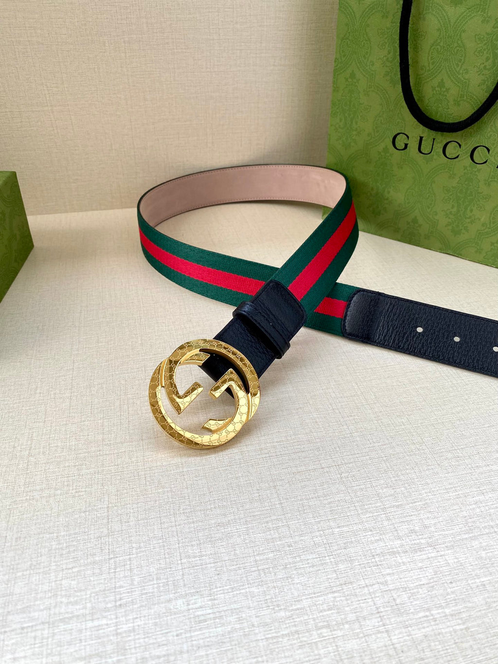 Gucci belt with navy strap and gold-toned circular buckle; green-red striped band