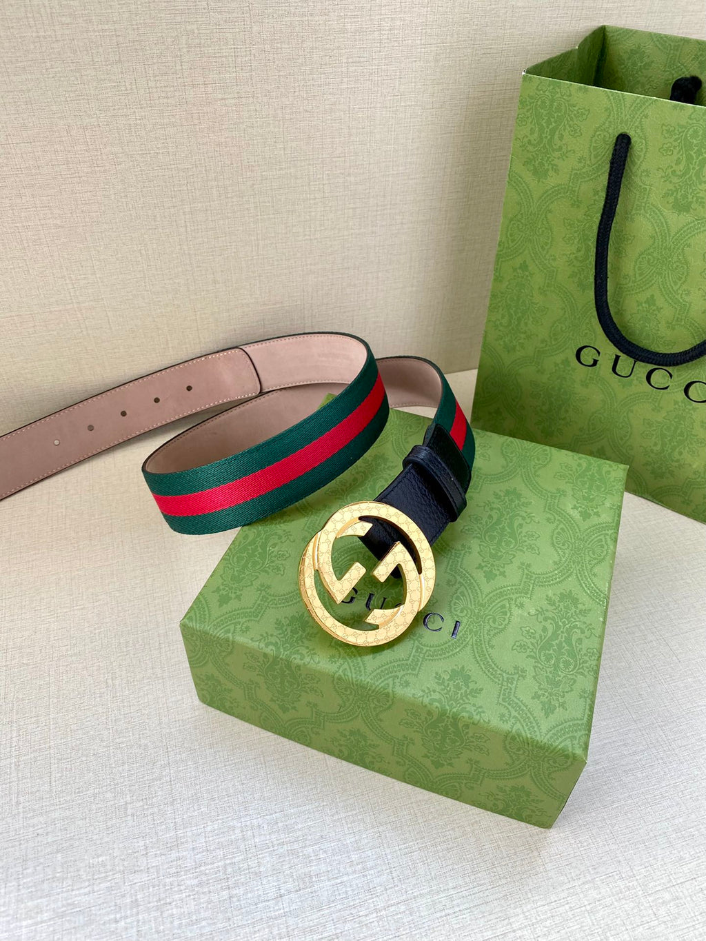 Gucci belt with navy strap, green-red striped band, and gold-toned GG buckle