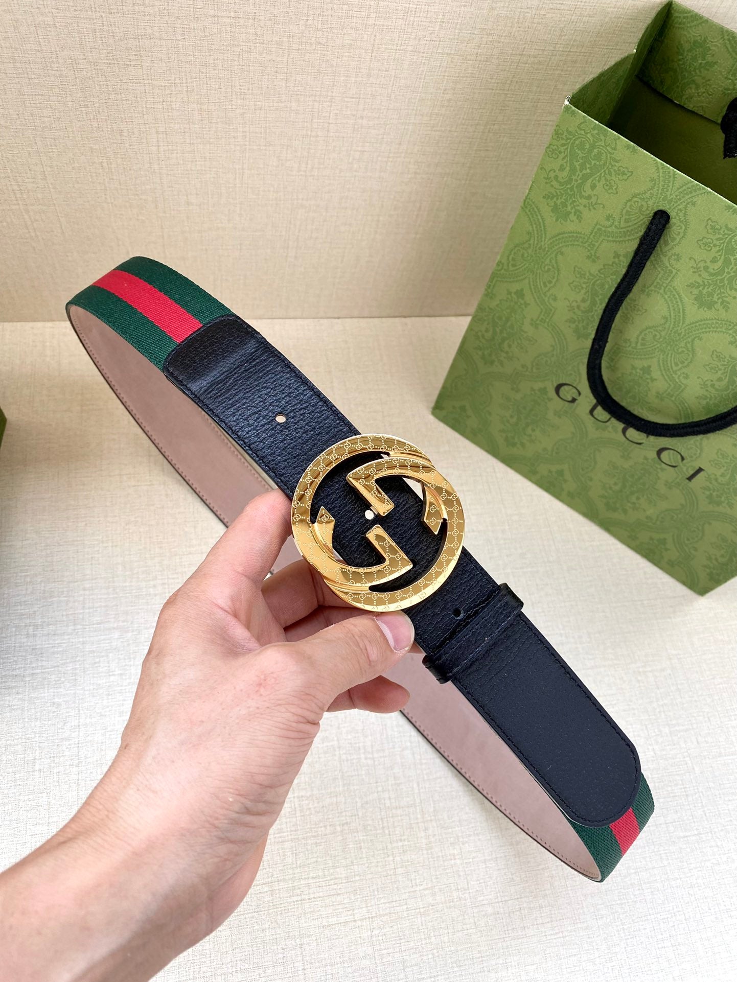 Gucci belt with navy strap and gold-toned GG buckle; green-red web stripe accents