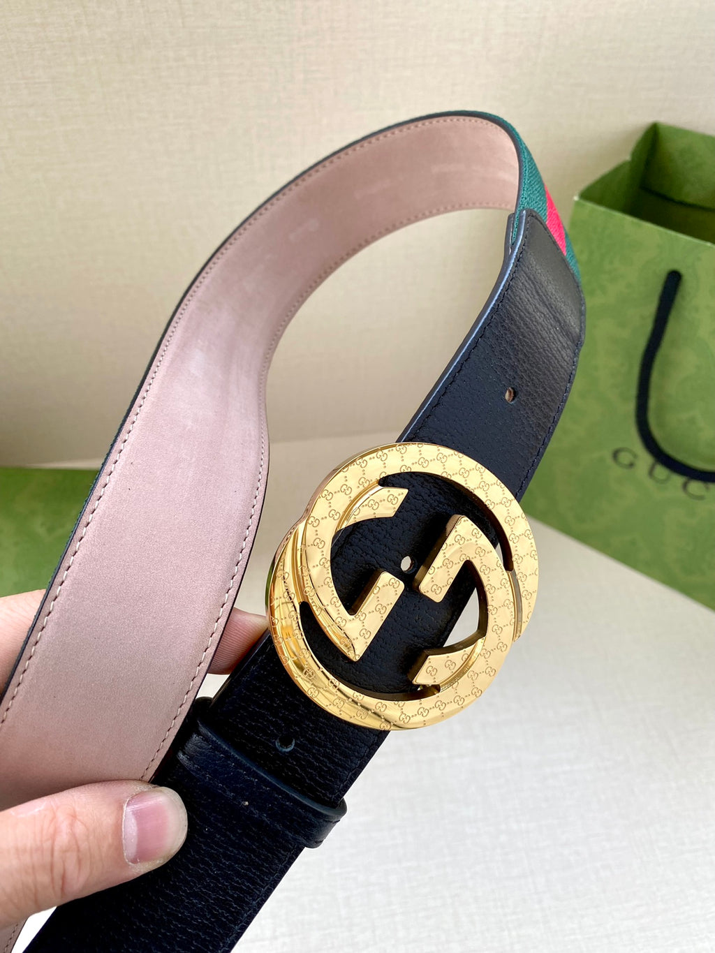 Gucci belt close-up: navy leather with gold-toned GG buckle and green-red striped edge