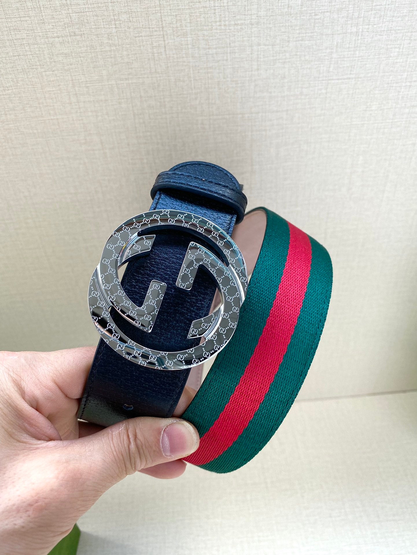 Gucci belt close-up: navy leather with patterned silver buckle ring and green-red stripe