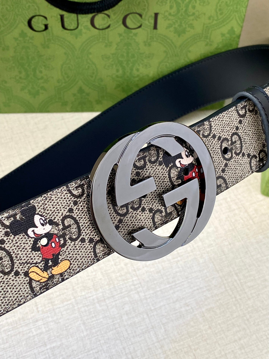 Gucci belt close-up, GG monogram Mickey print strap; silver interlocking G buckle