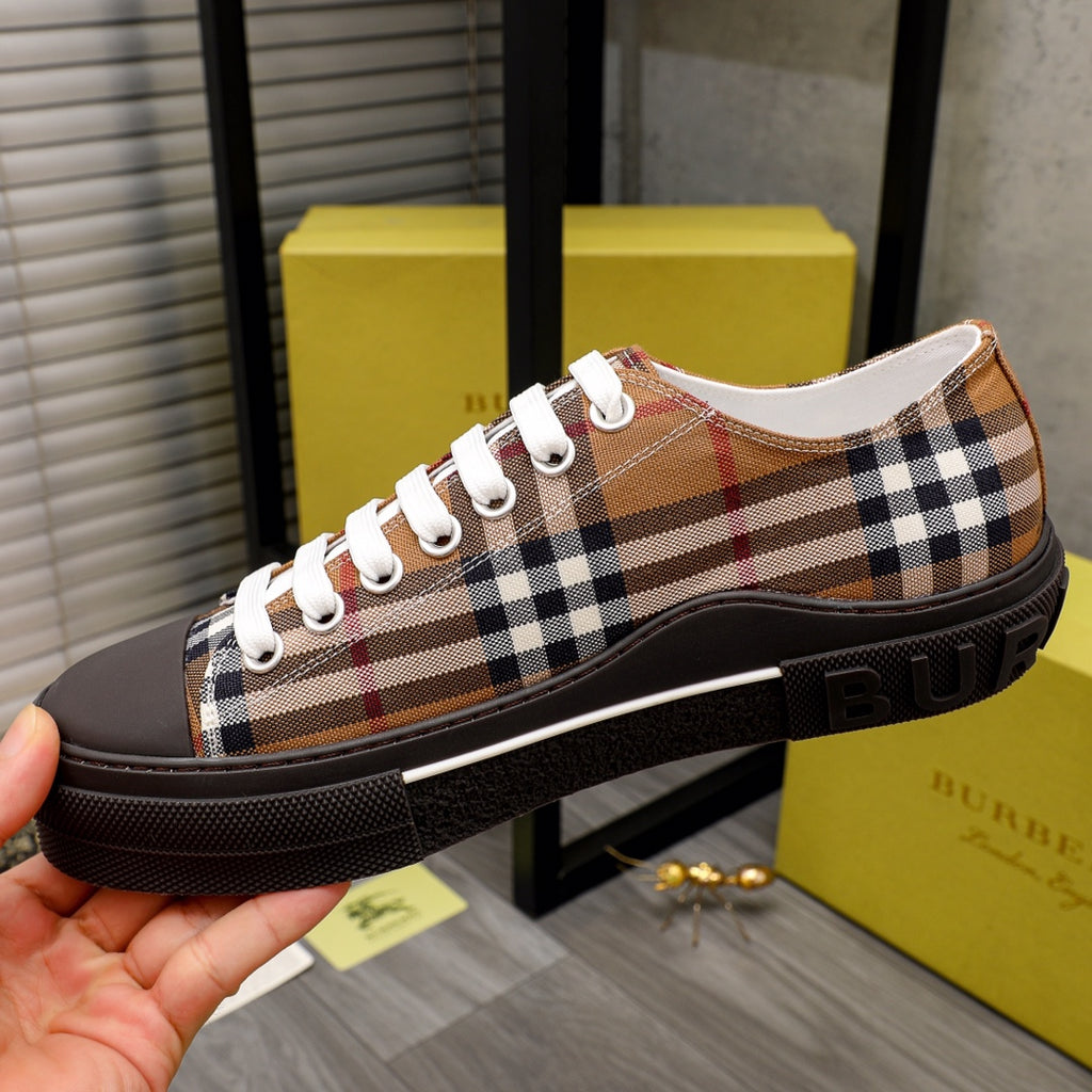Burberry plaid sneakers held in hand, showing white laces and dark rubber midsole