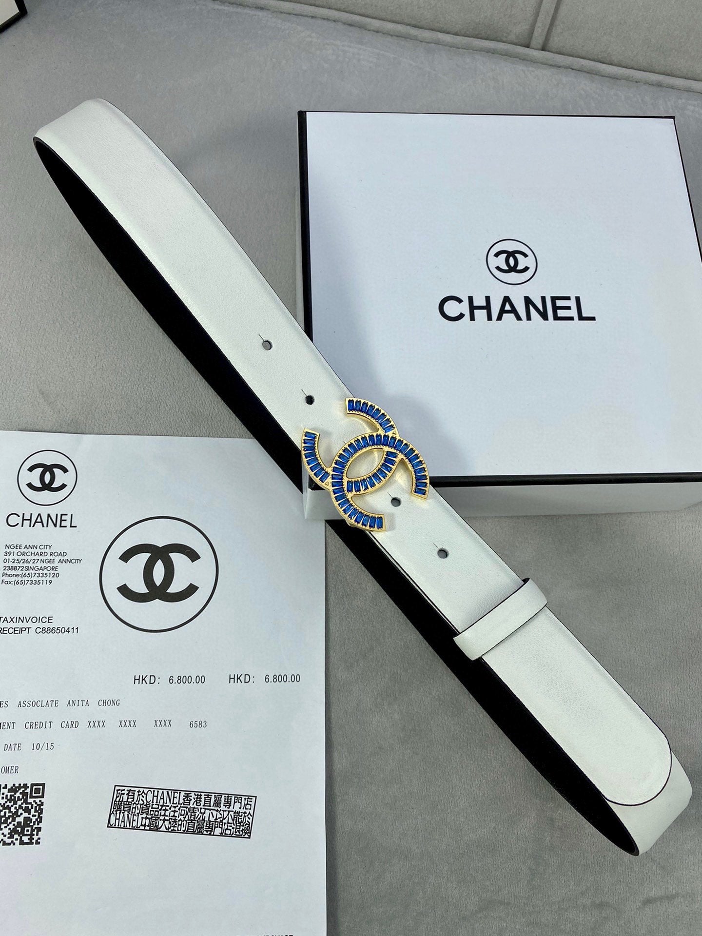 White leather belt with CHANEL logo buckle in gold and blue, flat view