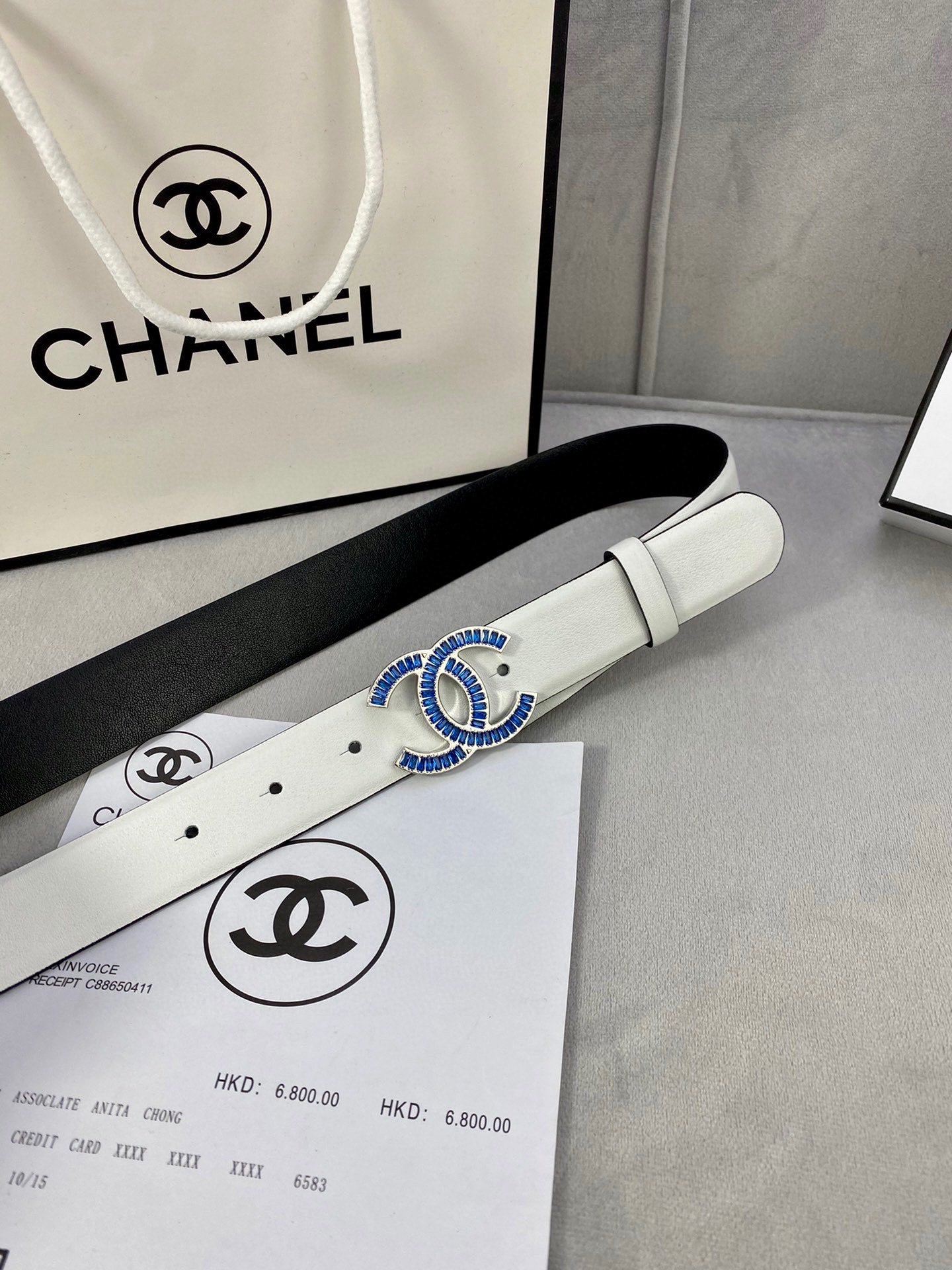 White leather belt with gold-and-blue CHANEL buckle on a product box