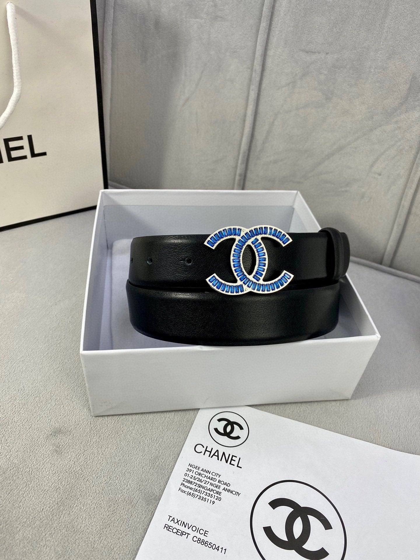 Black leather belt with blue CC-style embellished buckle, in open gift box