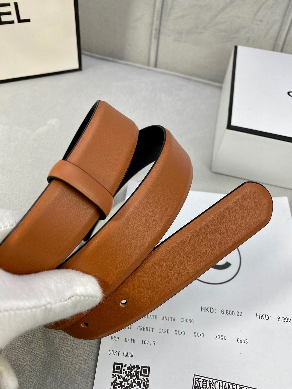 Tan leather belt with jeweled logo buckle and adjustable holes