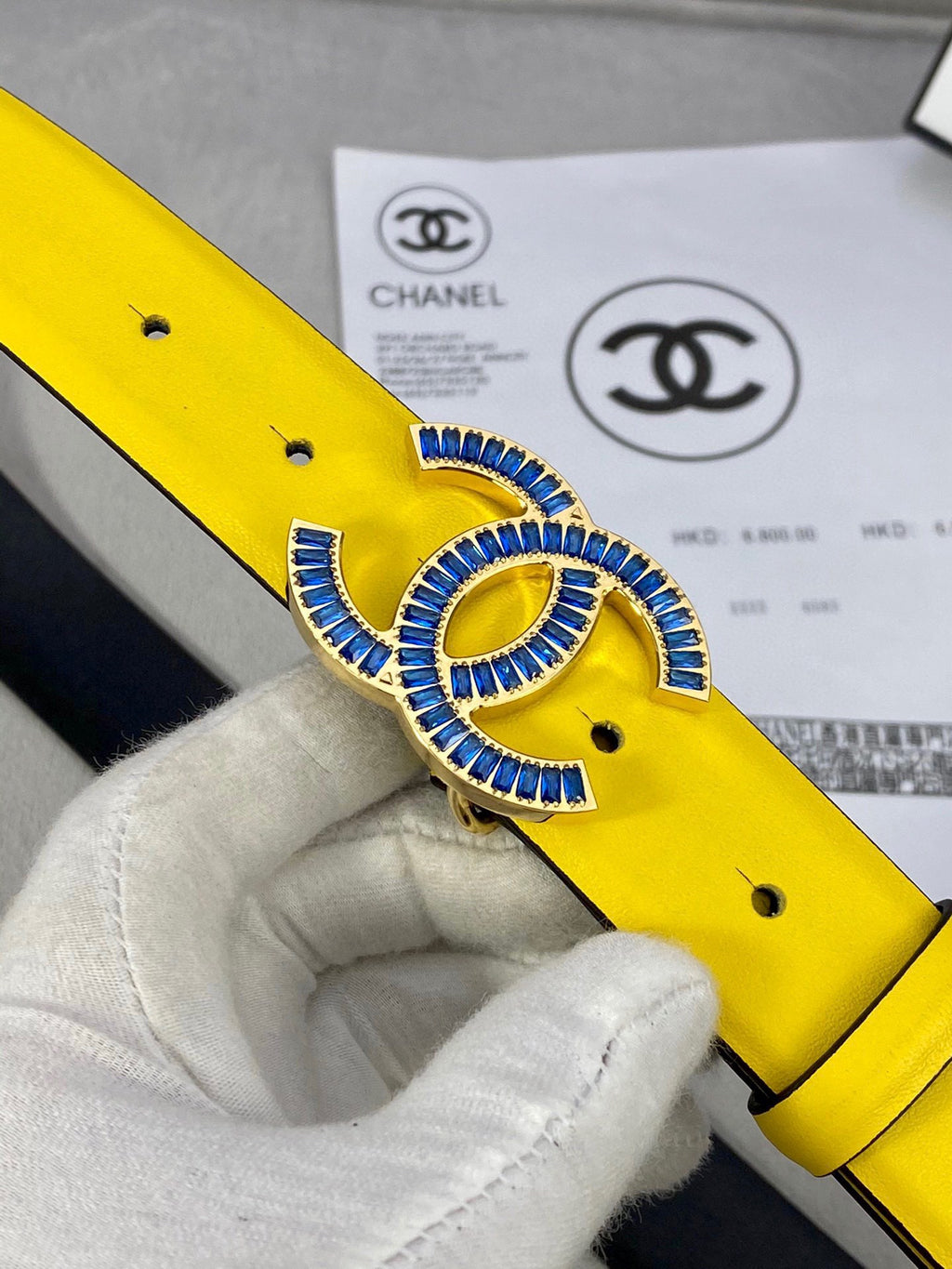 Chanel belt close-up: yellow leather with blue CC rhinestone buckle and black strap