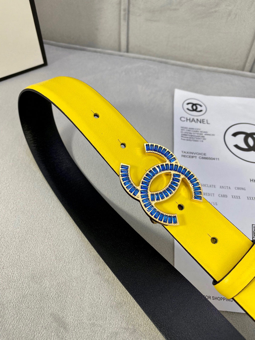 Chanel belt side view, yellow leather strap with blue CC buckle and black interior