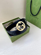 Navy leather belt with gold-toned circular GG logo buckle