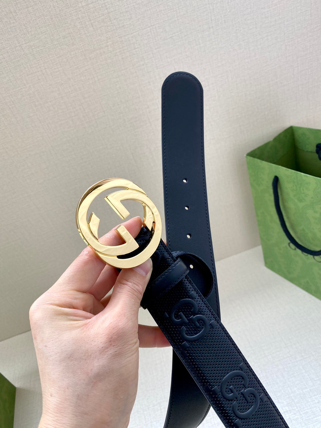 Navy leather belt with circular gold-tone logo buckle