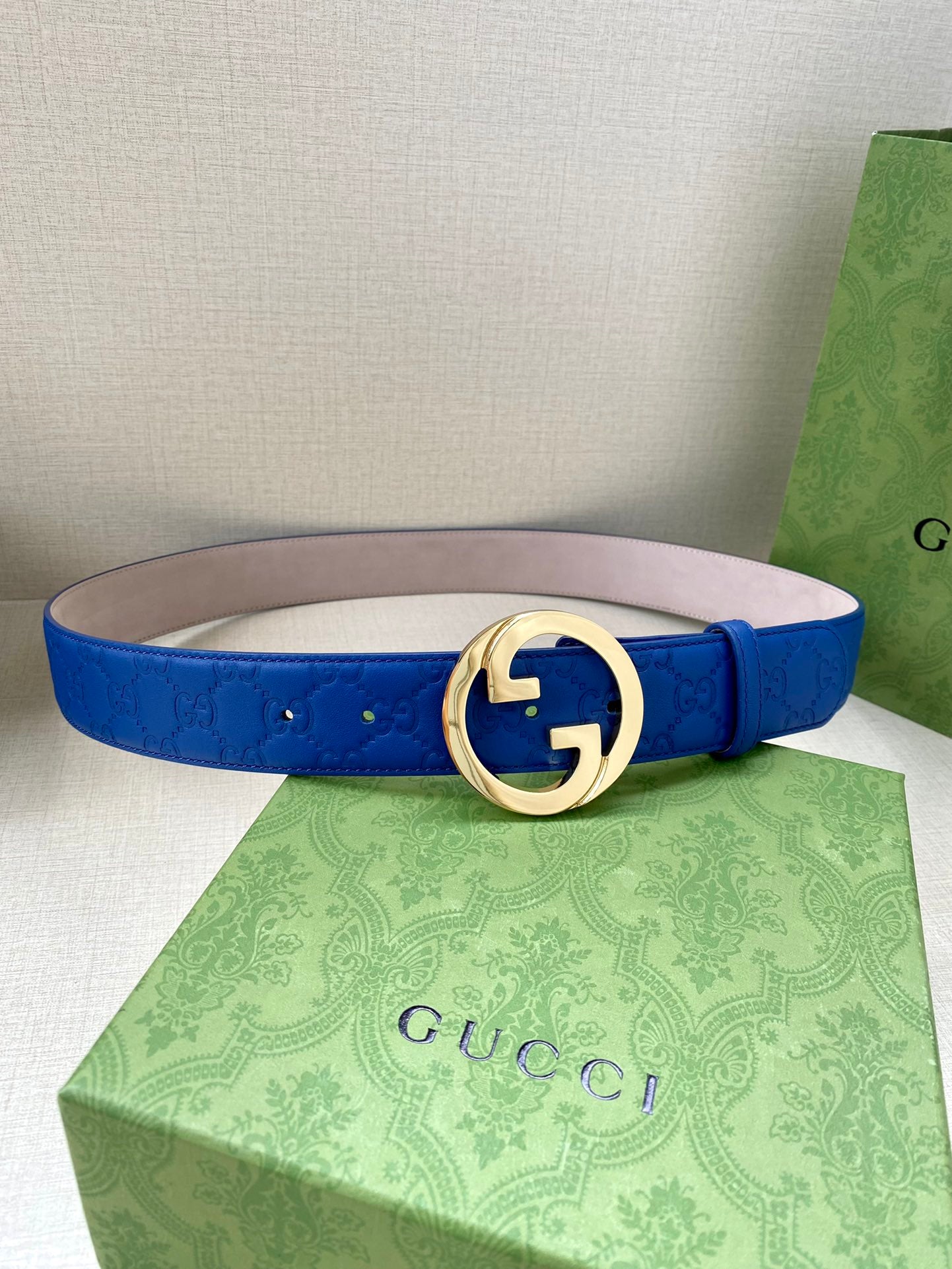 Gucci belt blue leather with gold-tone interlocking GG buckle and textured strap.