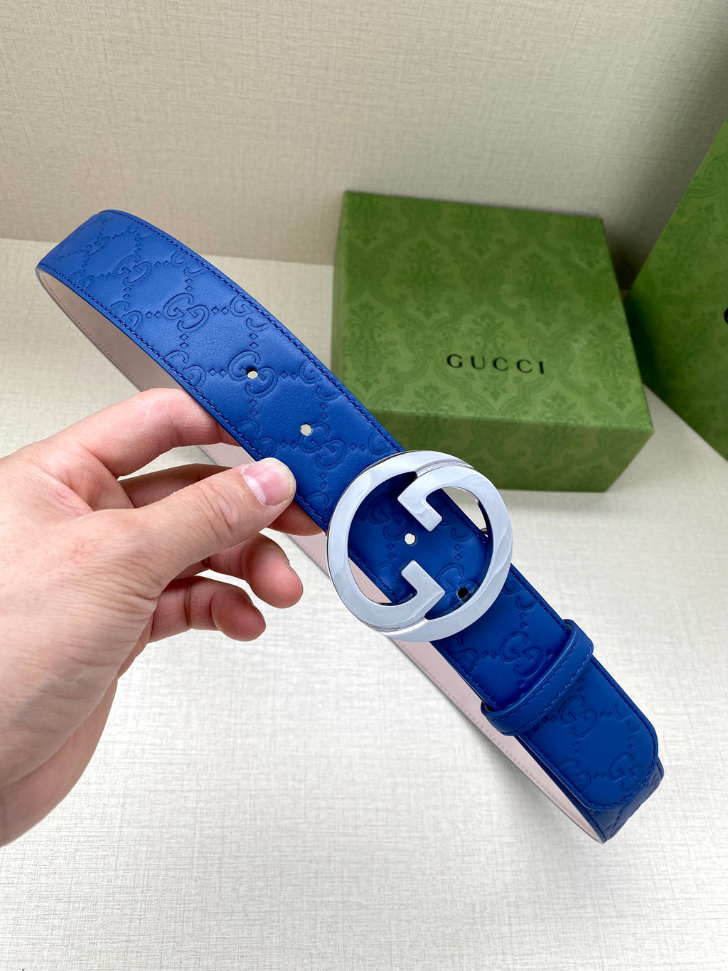Gucci belt with blue leather and silver interlocking GG buckle, textured finish.