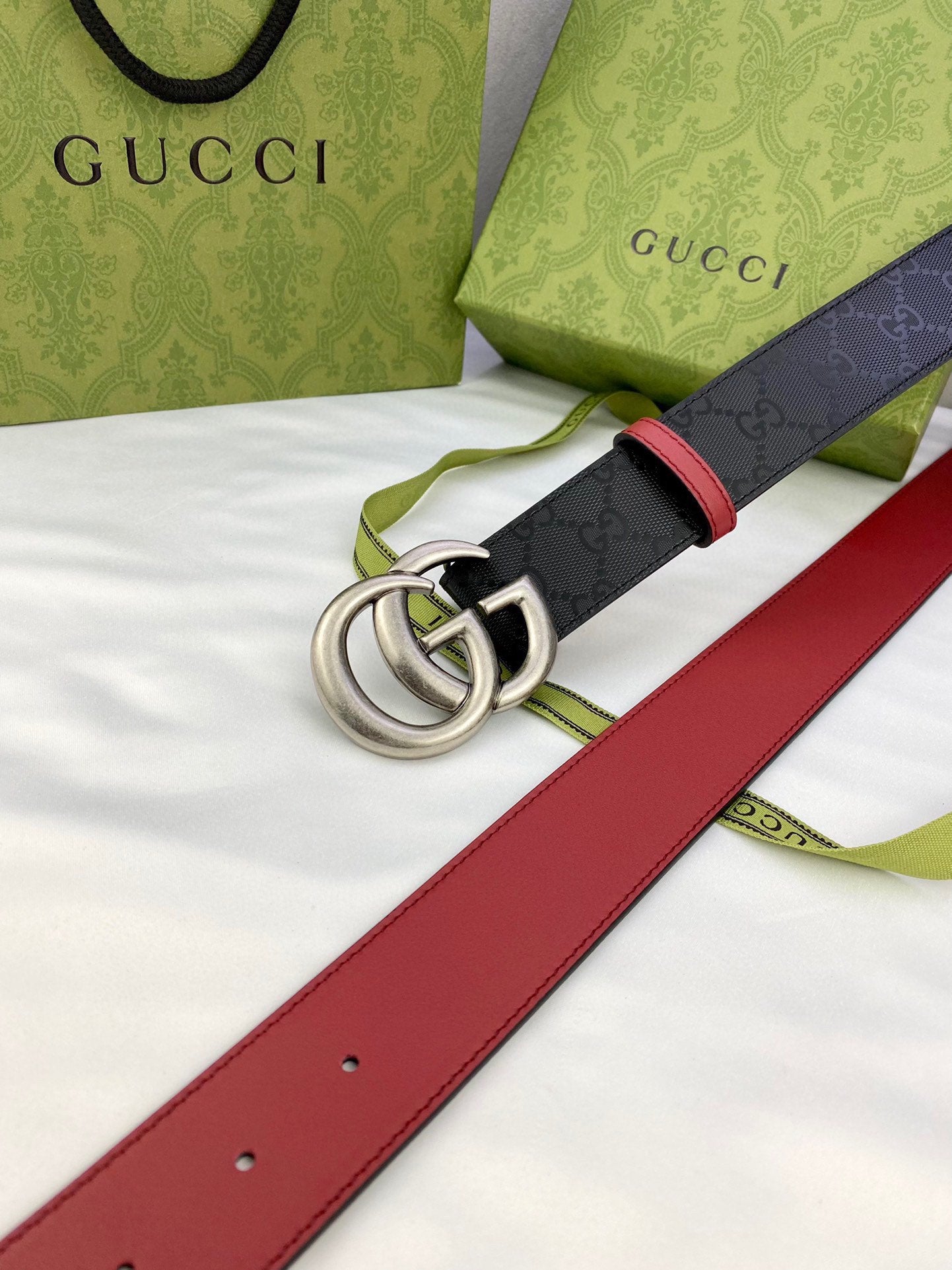 Gucci belt detail with black logo leather, red trim, and silver-tone double G buckle