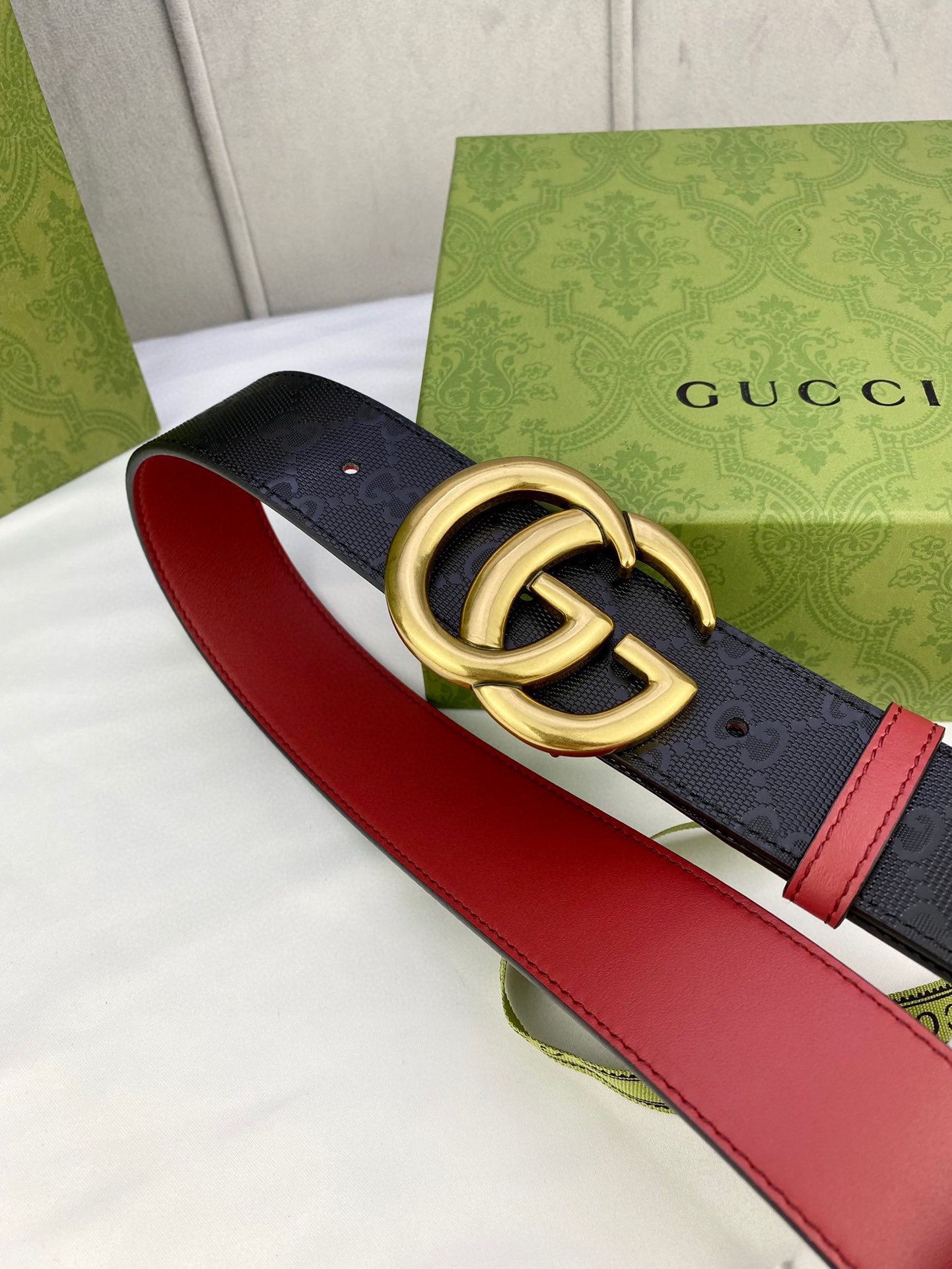 Gucci belt close-up: black monogram strap with red edges and gold-tone double G buckle