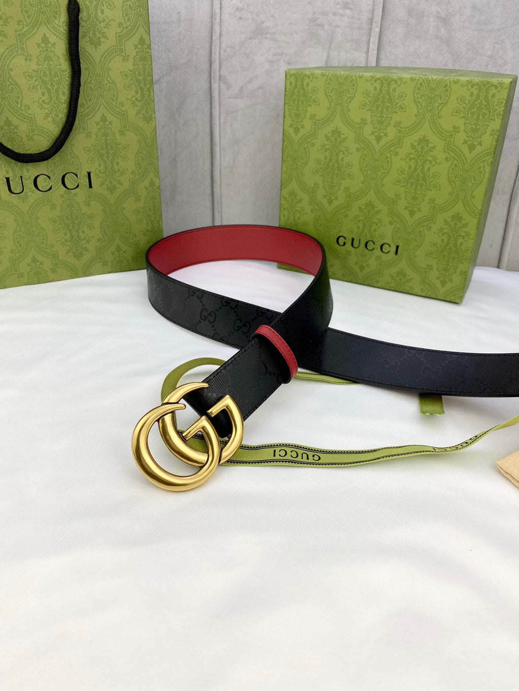 Gucci belt with black logo leather, red lining, and gold-tone interlocking double G buckle