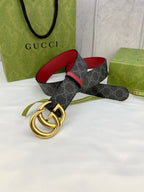 Gucci belt with dark GG-pattern strap, red trim, and gold double-G buckle on display