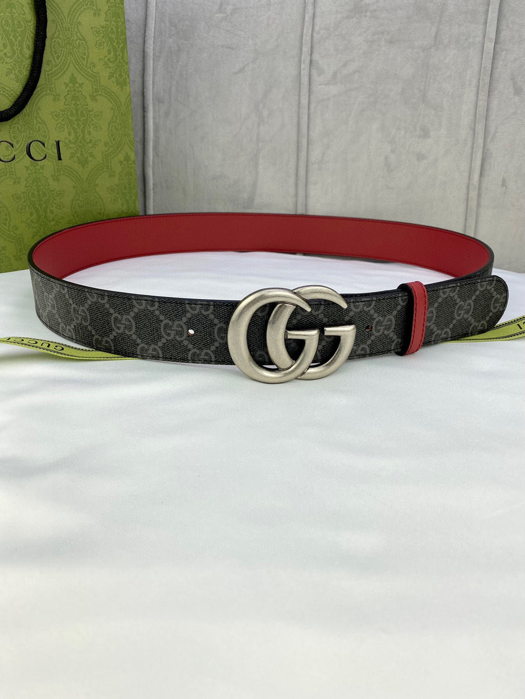 Gucci belt with dark GG-pattern strap, red edge trim, and silver double-G buckle