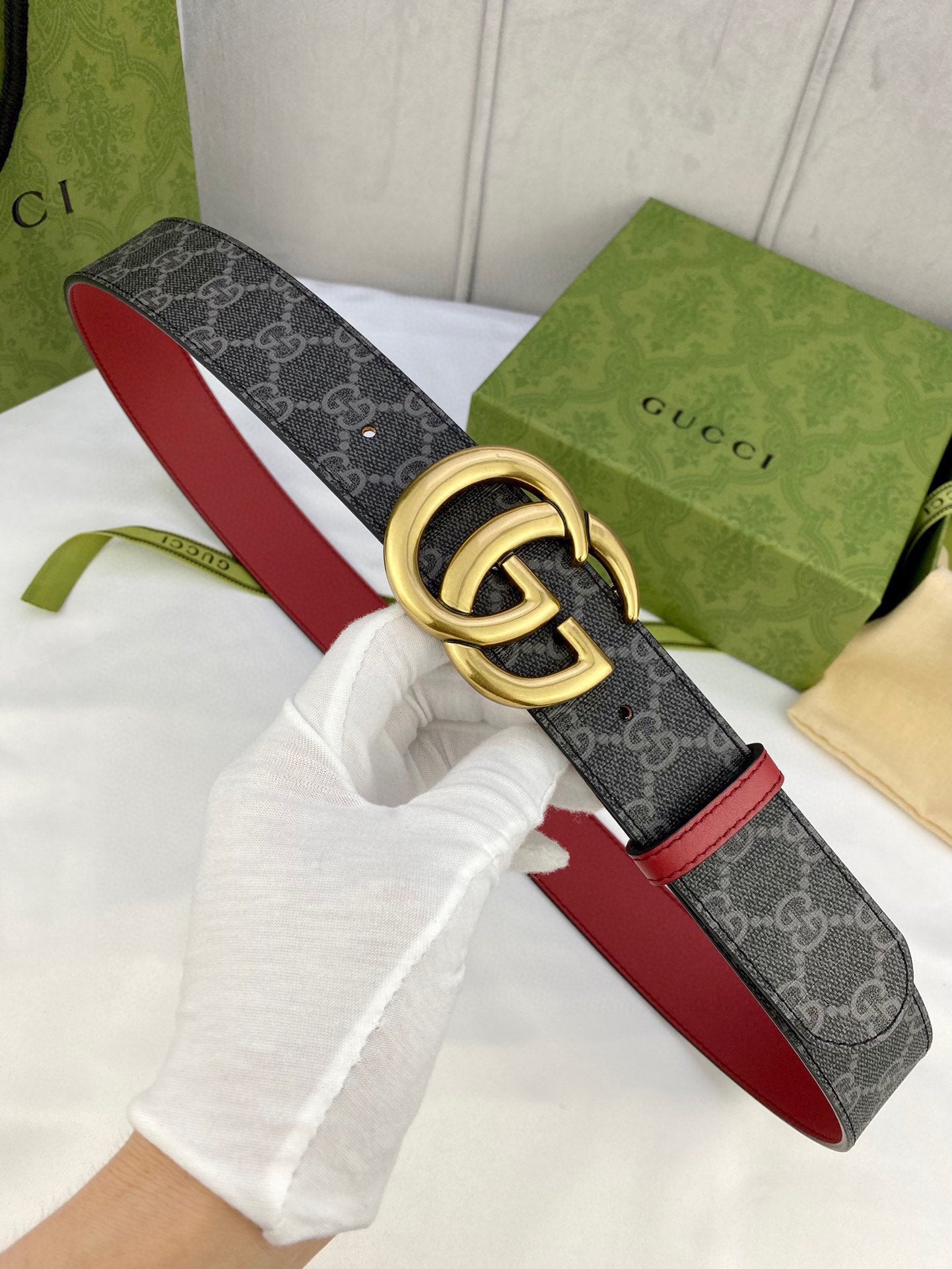 Gucci belt with dark GG-pattern strap, red trim, and gold double-G buckle