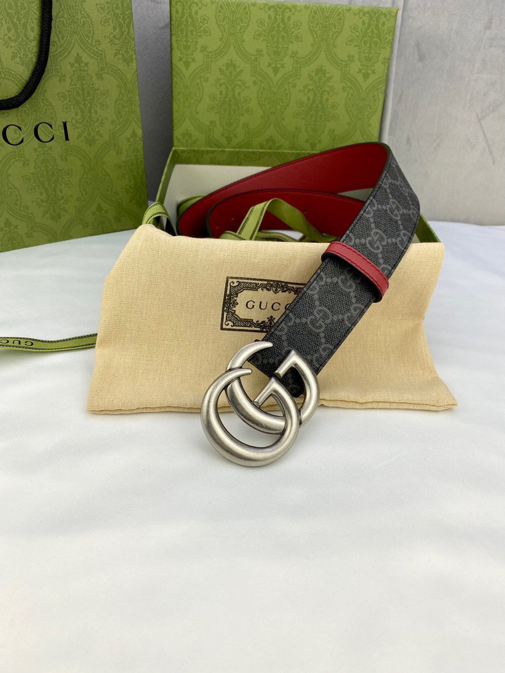 Gucci belt with dark GG monogram strap, red edge trim, and silver double-G buckle