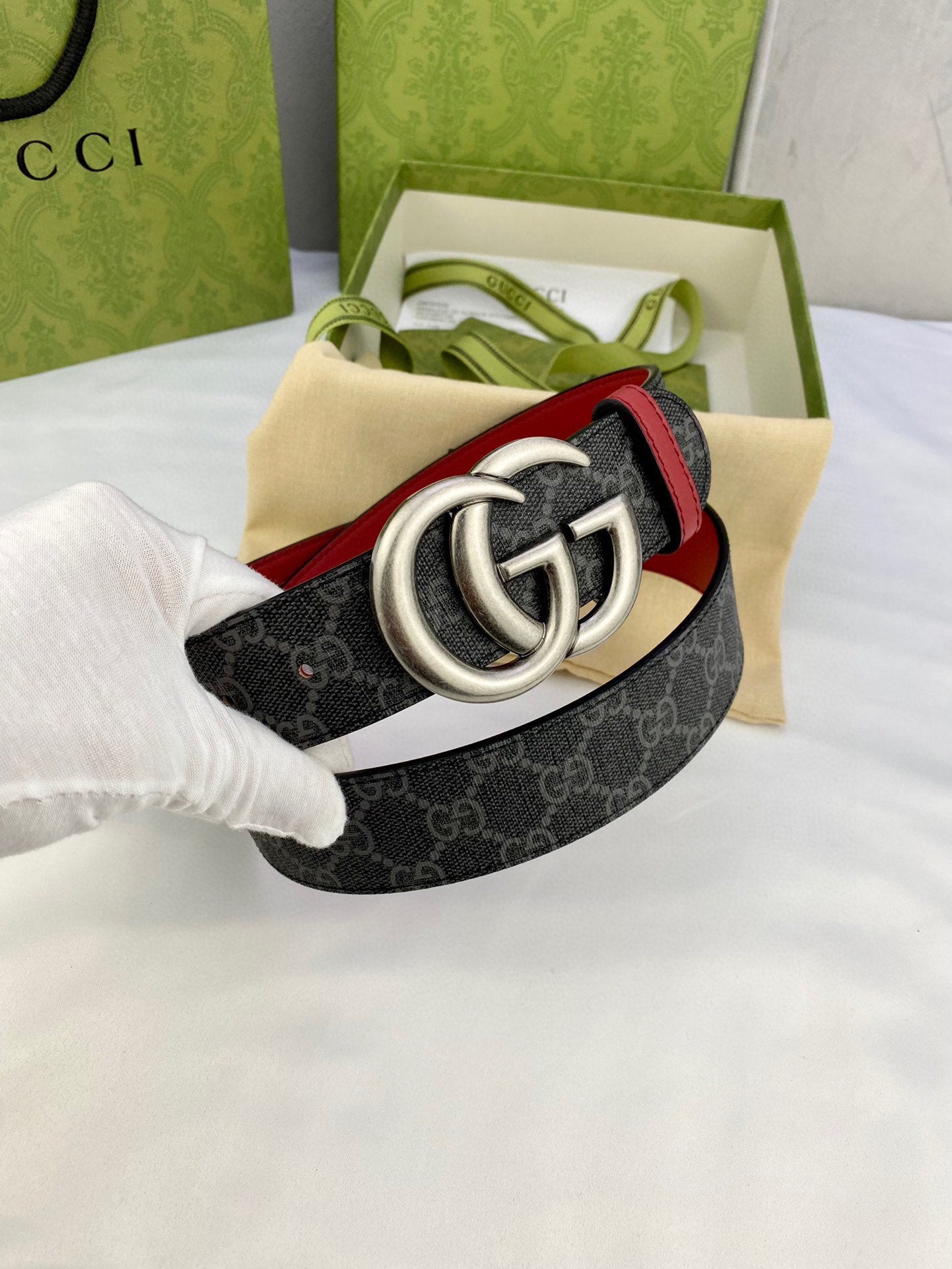 Gucci belt in packaging: dark GG-pattern strap with red trim and silver double-G buckle