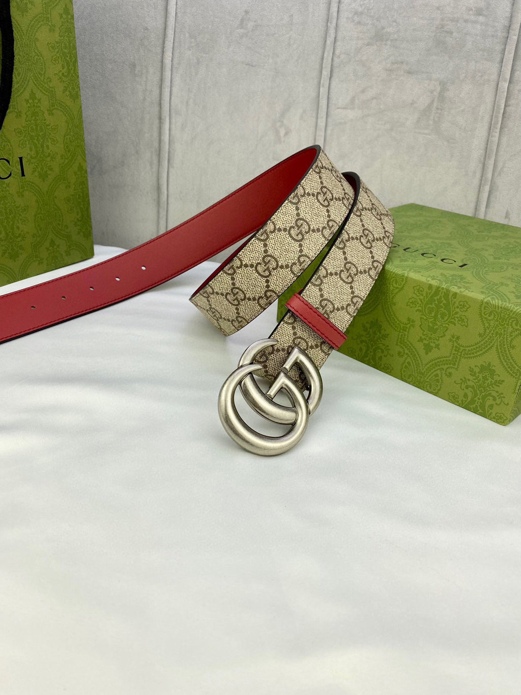 Gucci belt laid flat, GG monogram canvas with red leather sides and silver double-G buckle
