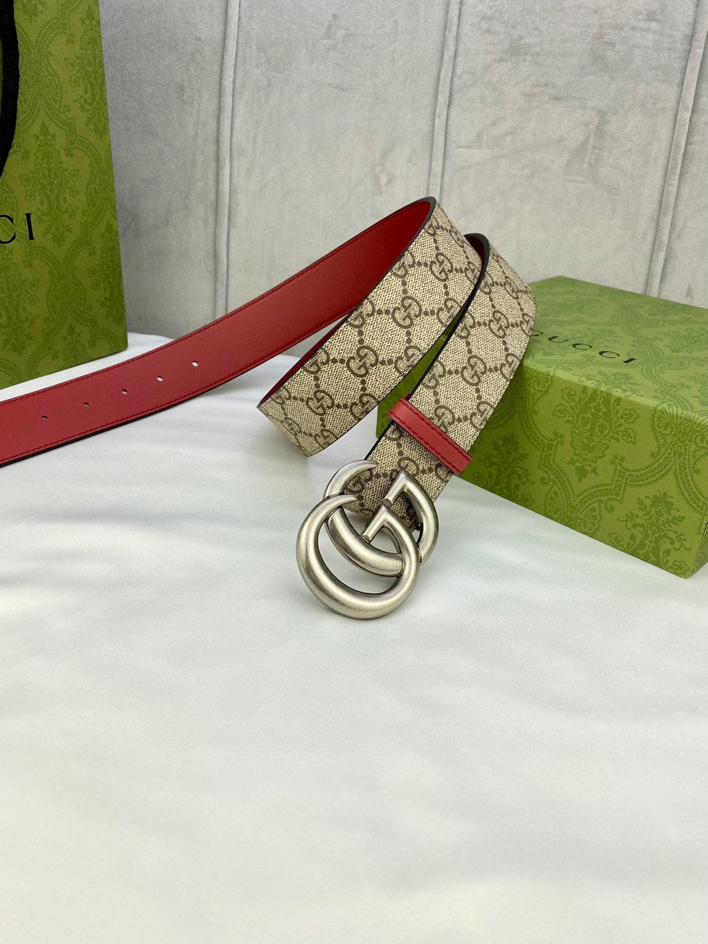 Gucci belt laid flat, GG monogram canvas with red leather sides and silver double-G buckle