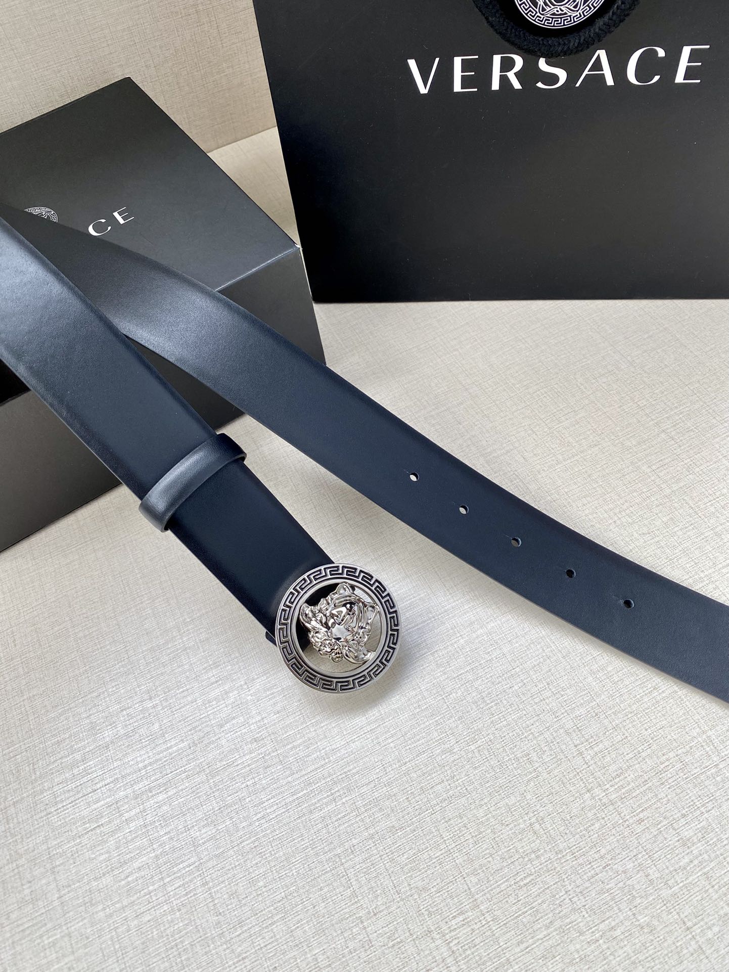 Dark blue leather belt with gold Medusa logo buckle and perforated holes