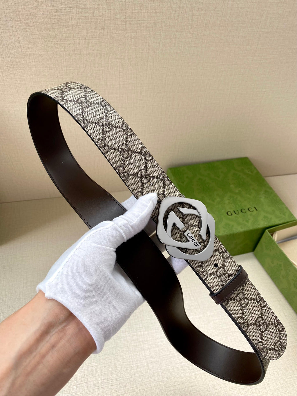 Gucci belt, GG canvas strap with silver interlocking G buckle held in hand