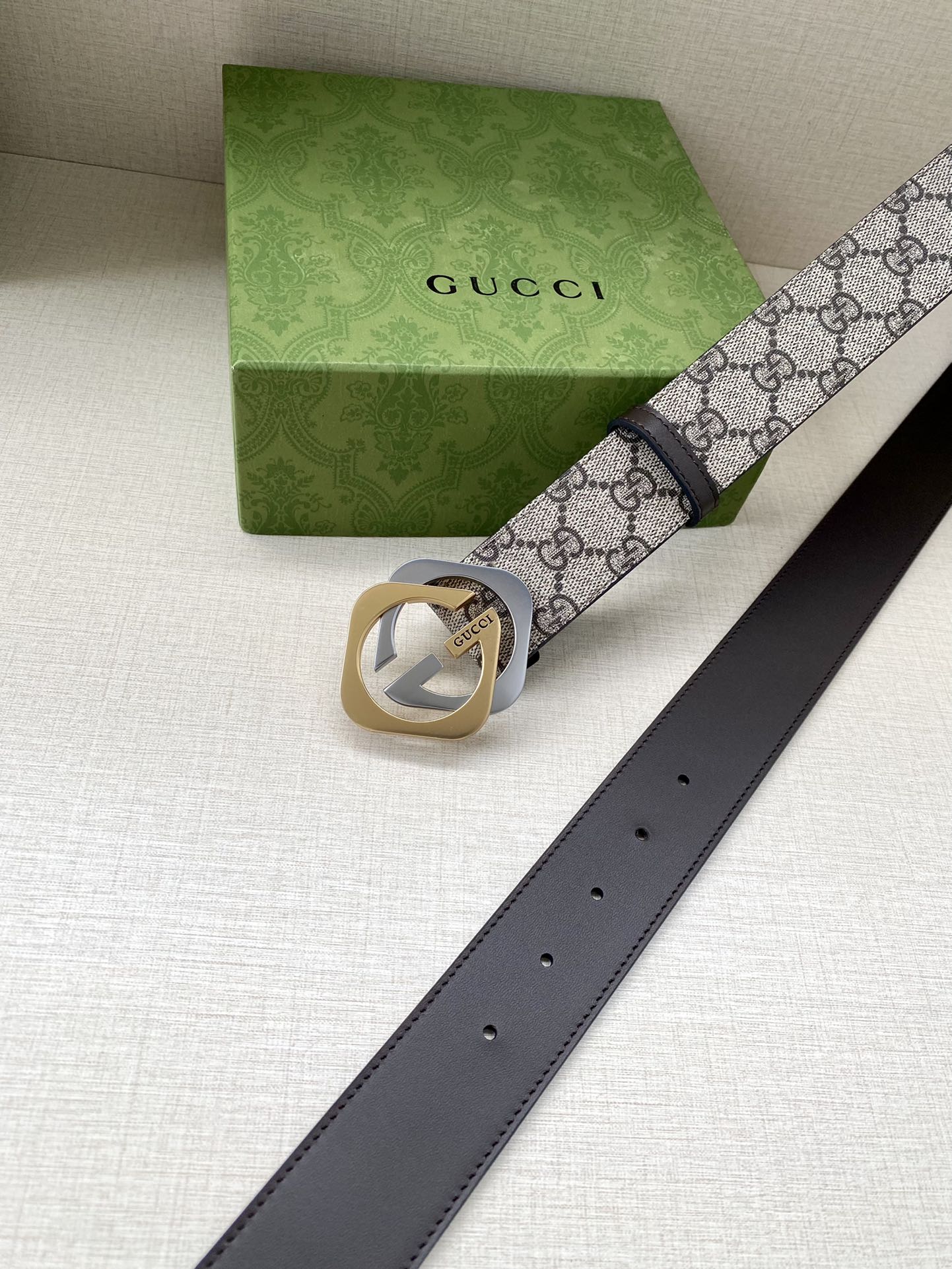 GG monogram belt with dark brown leather strap, gold buckle, and belt holes visible
